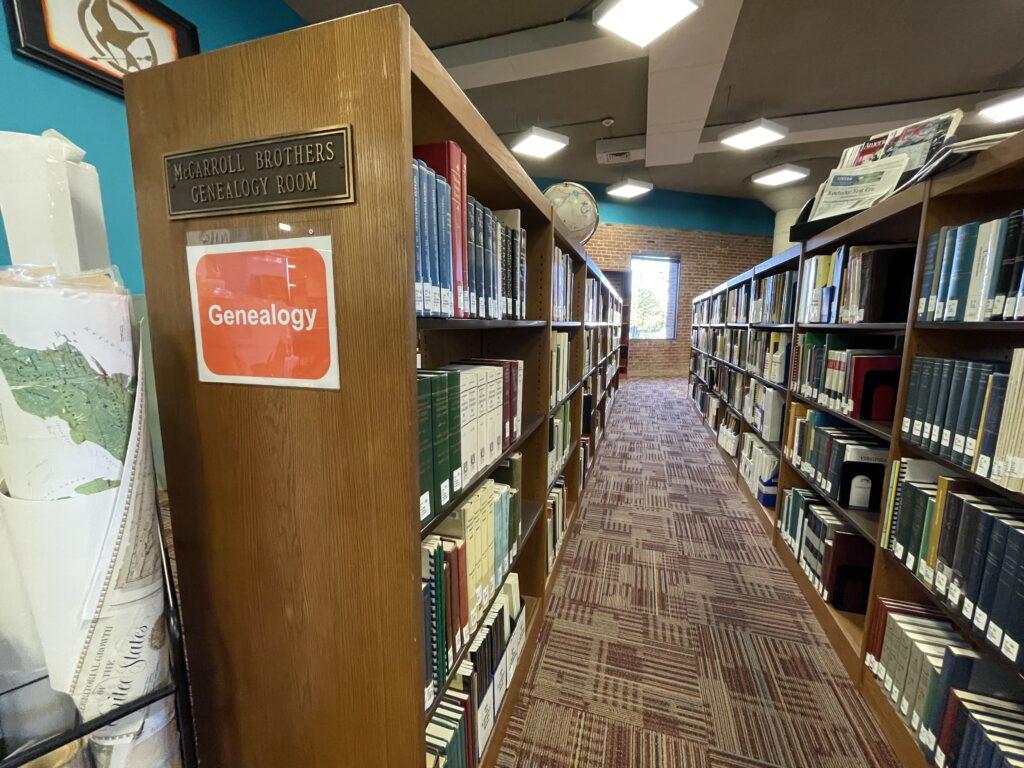 A photo of bookshelves with a stand of maps in the foreground